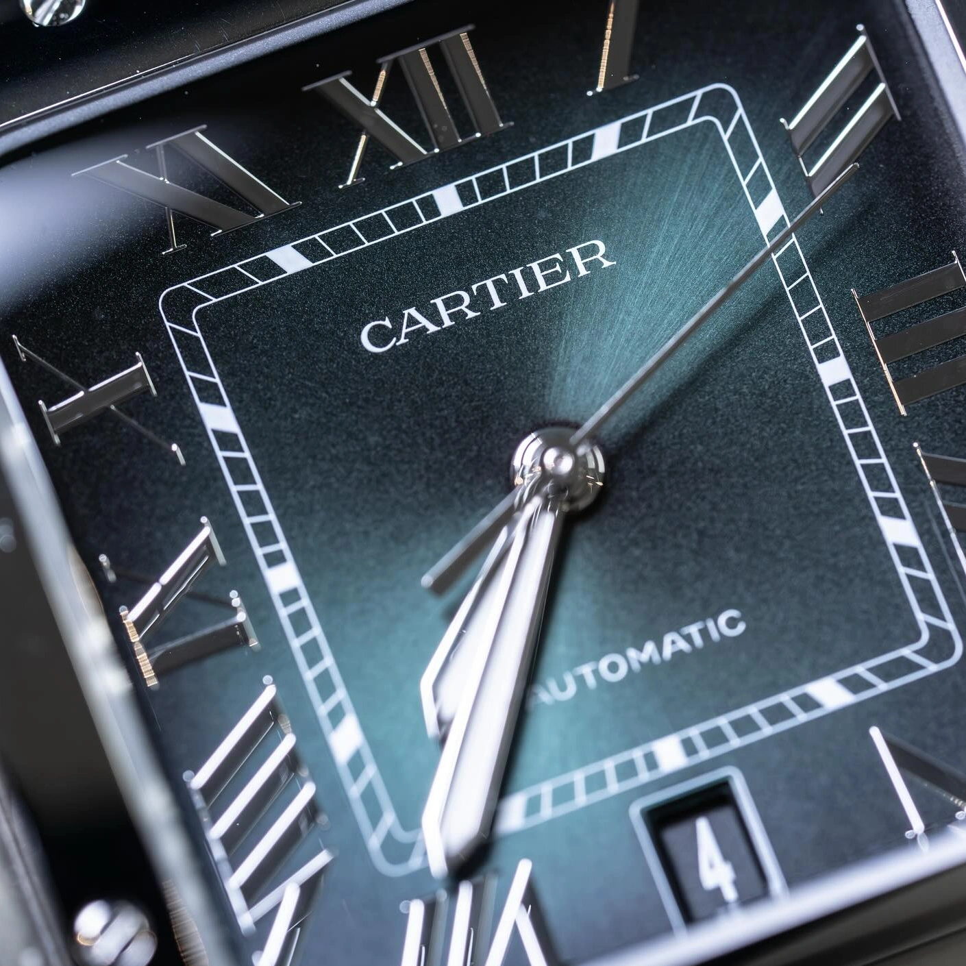 Close-up of a green Cartier Santos dial with Roman numerals and date display